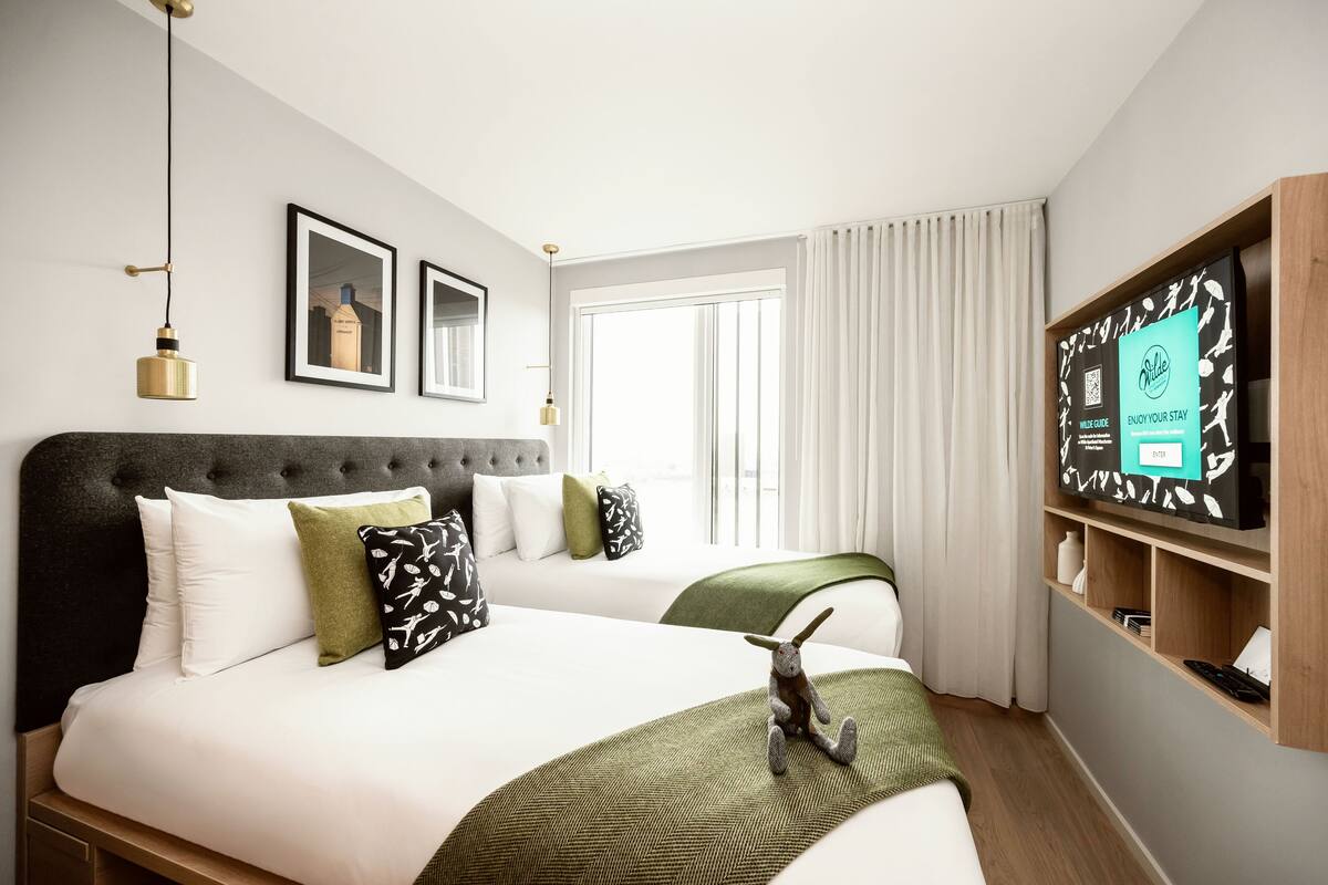 A hotel room with a large bed, a television, and a window with curtains.