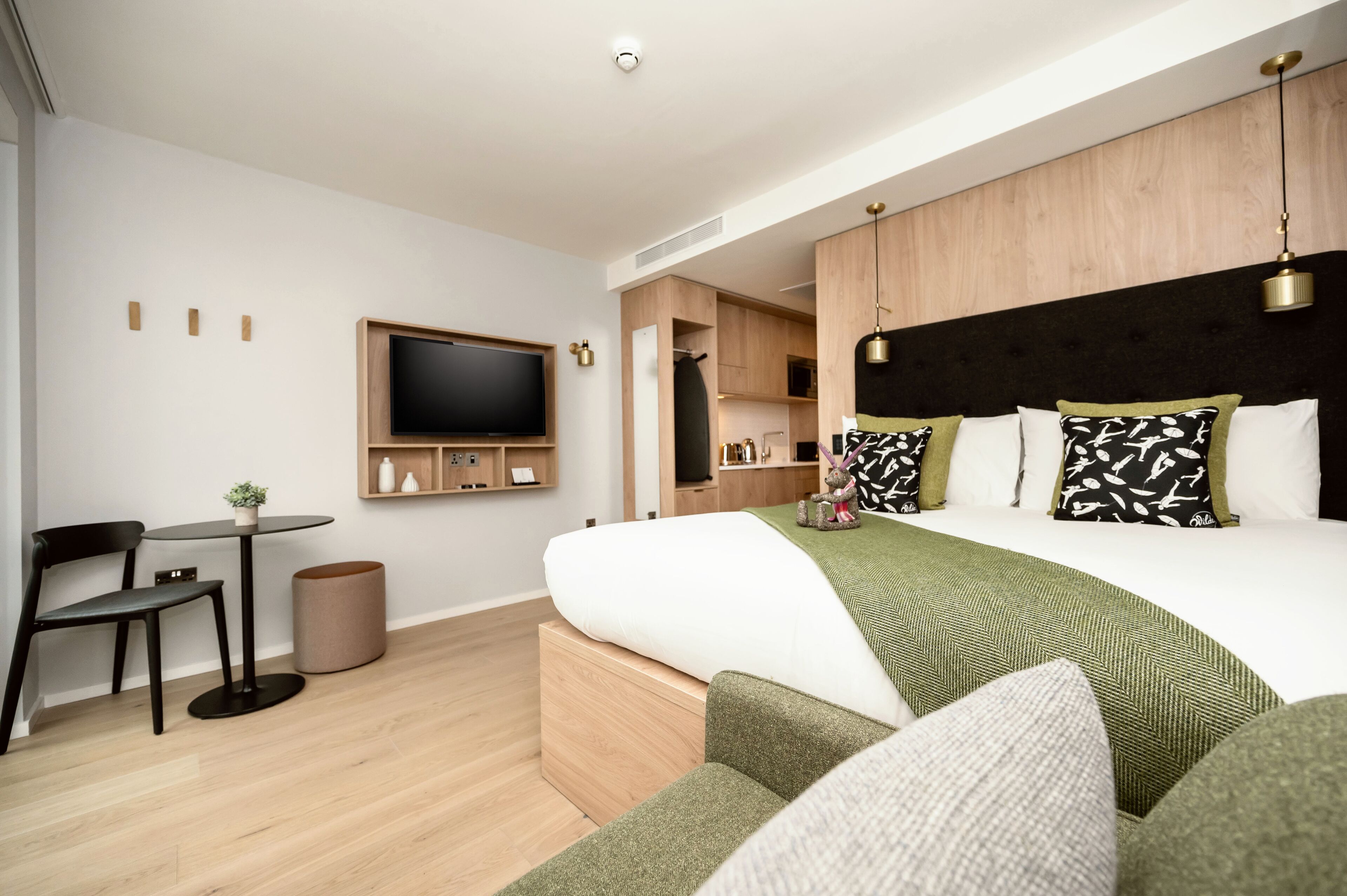 Et moderne hotelværelse med en stor seng, et fjernsyn, et lille bord og et siddeområde.