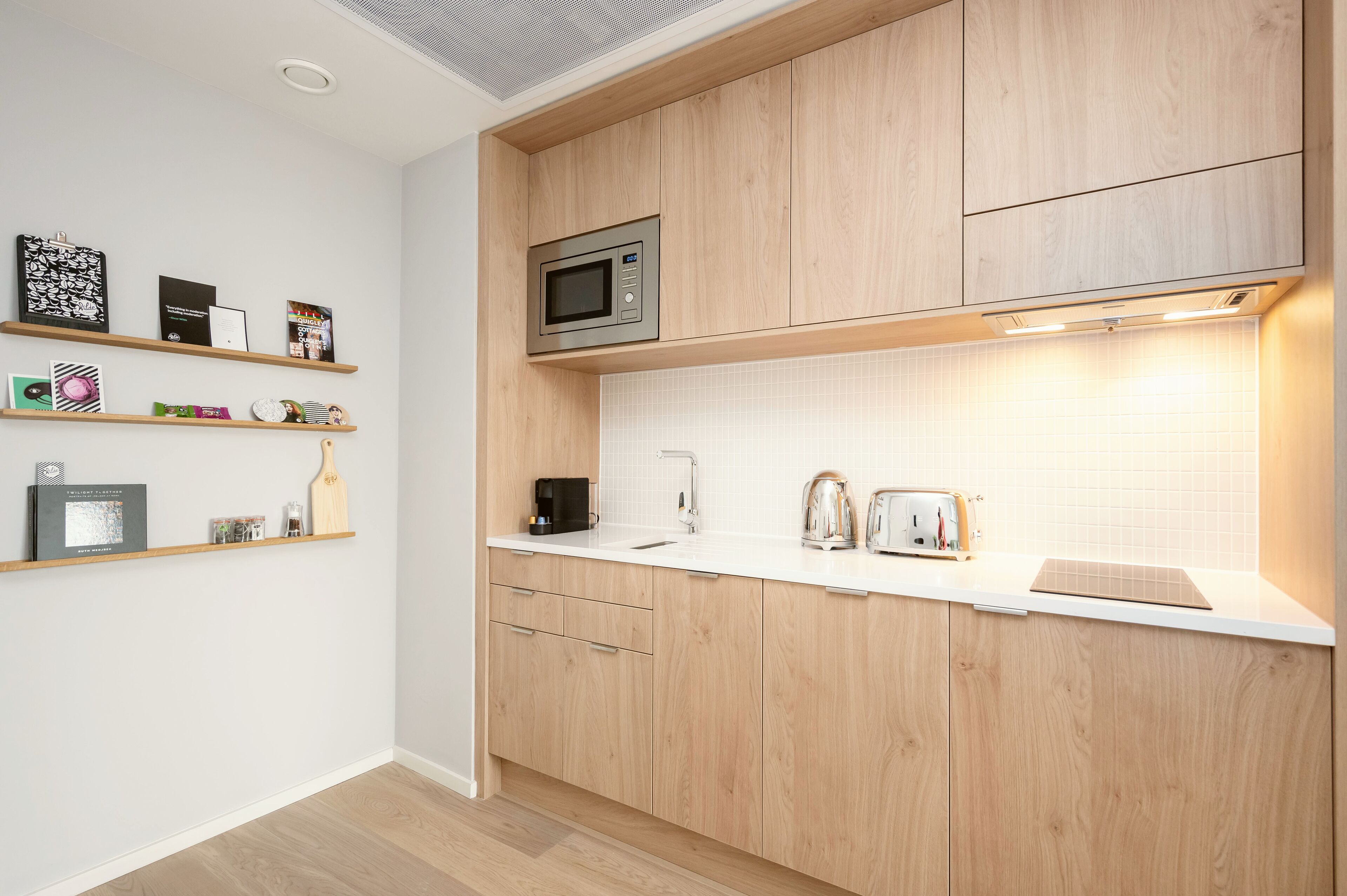A modern kitchen with wooden cabinets, a microwave, a sink, and various kitchen appliances.