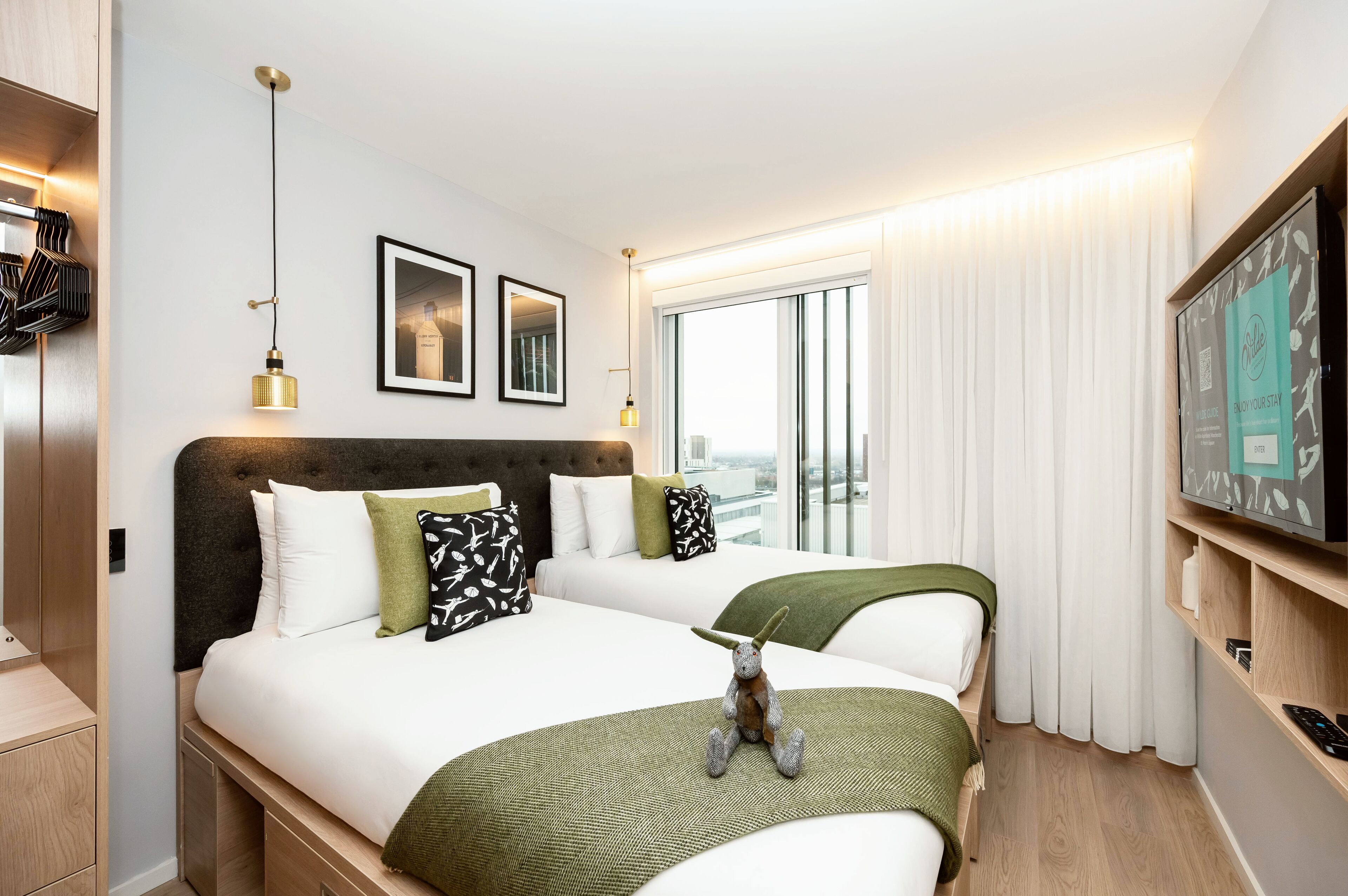 A hotel room with a large bed, a small table, a TV, and a window with curtains.