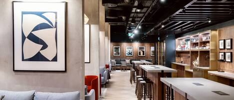 A modern bar area with high stools, a sofa, and a framed abstract artwork on the wall.
