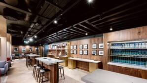 Un área de bar moderna con paneles de madera, taburetes y una exhibición de vasos.