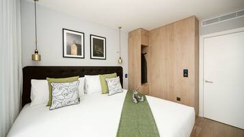Une chambre d’hôtel moderne avec un grand lit, une armoire en bois et un tableau encadré au mur.