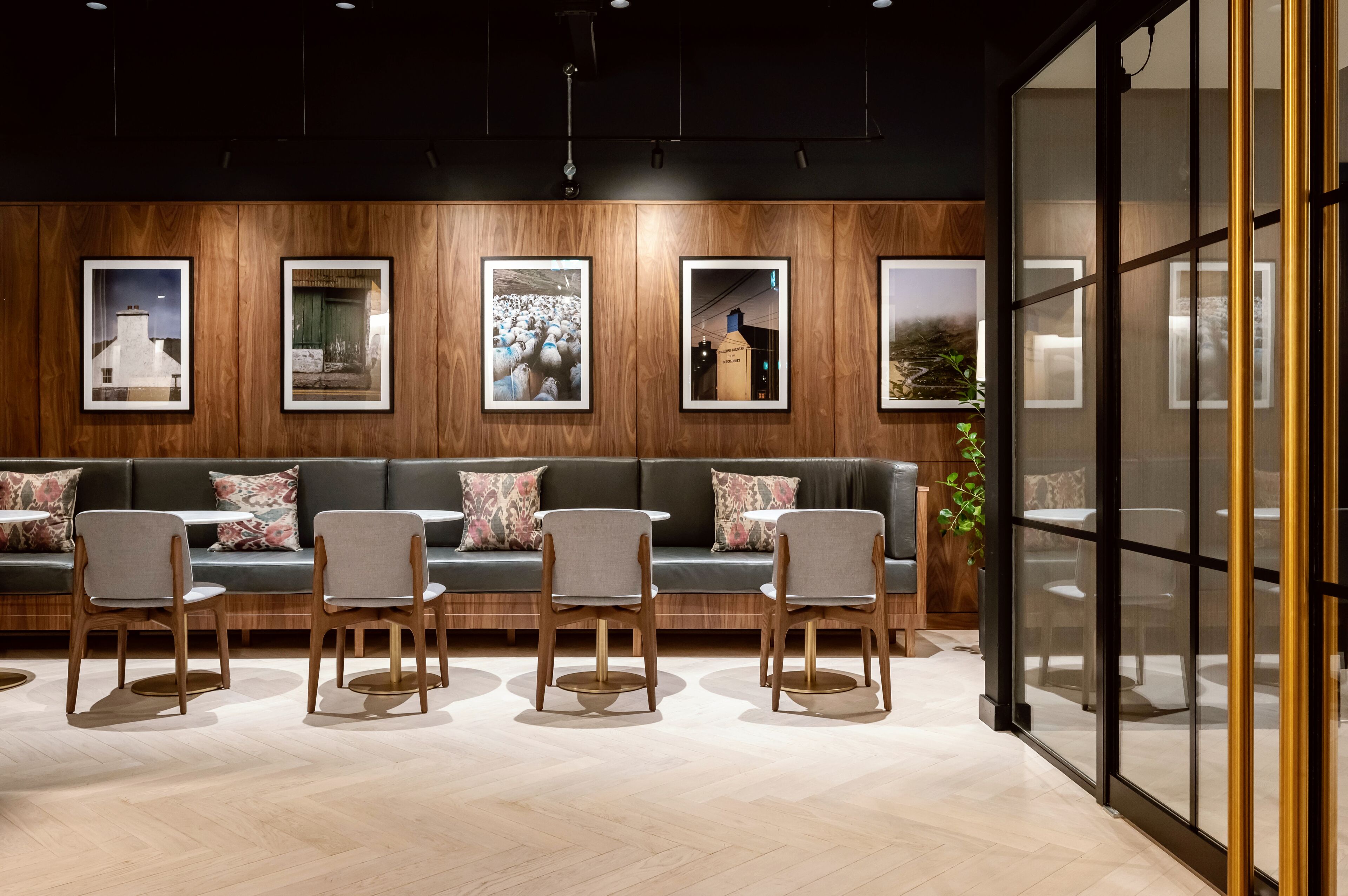 A reception area with a wooden panel wall, a dark green sofa with patterned cushions, and a row of grey chairs.