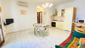 A compact living space with a dining area, kitchenette, and a TV mounted on the wall. - Sa Domo Lada 2 (San Teodoro)