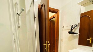 A bathroom with a glass shower enclosure, a wooden door, a white sink, and a mirror above the sink. - Sa Domo Lada 2 (San Teodoro)