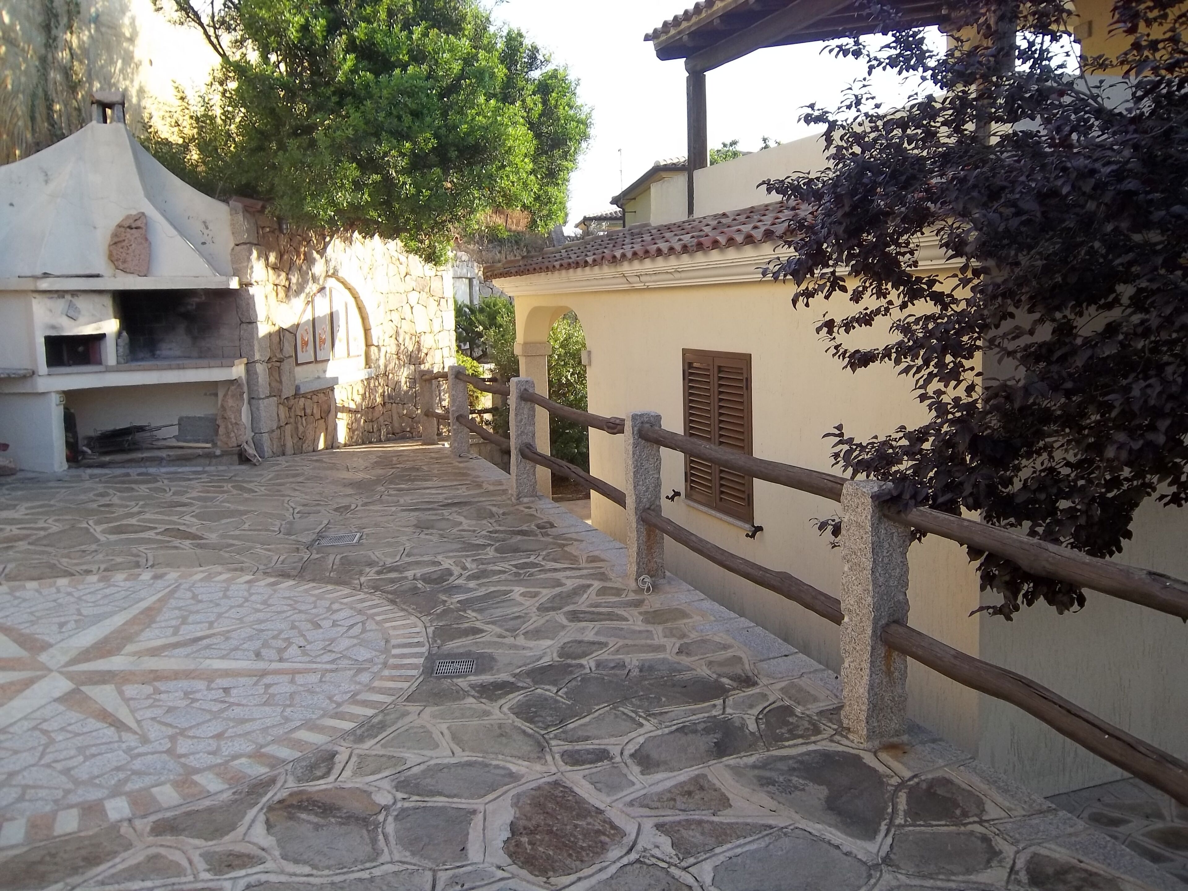 A stone-paved courtyard with a stone wall and wooden railing.