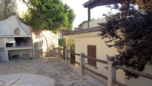 A stone-paved courtyard with a stone wall and wooden railing. - Sa Domo Lada 2 (San Teodoro)