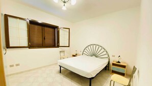 A bedroom with a bed, a chair, a nightstand, and a desk. - Sa Domo Lada 2 (San Teodoro)
