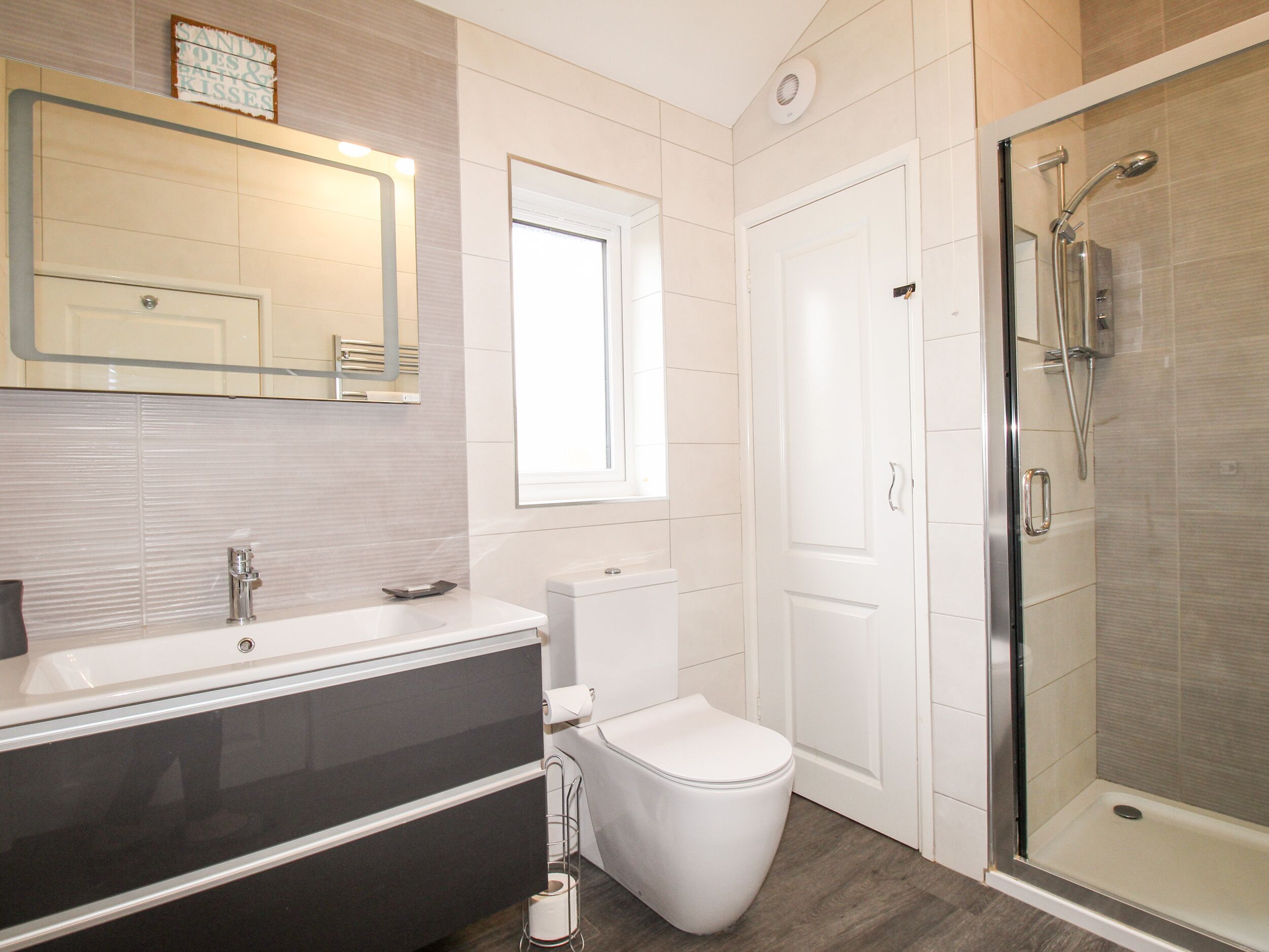 Une salle de bain moderne avec un lavabo blanc, un meuble-lavabo, des toilettes et une douche à parois de verre.
