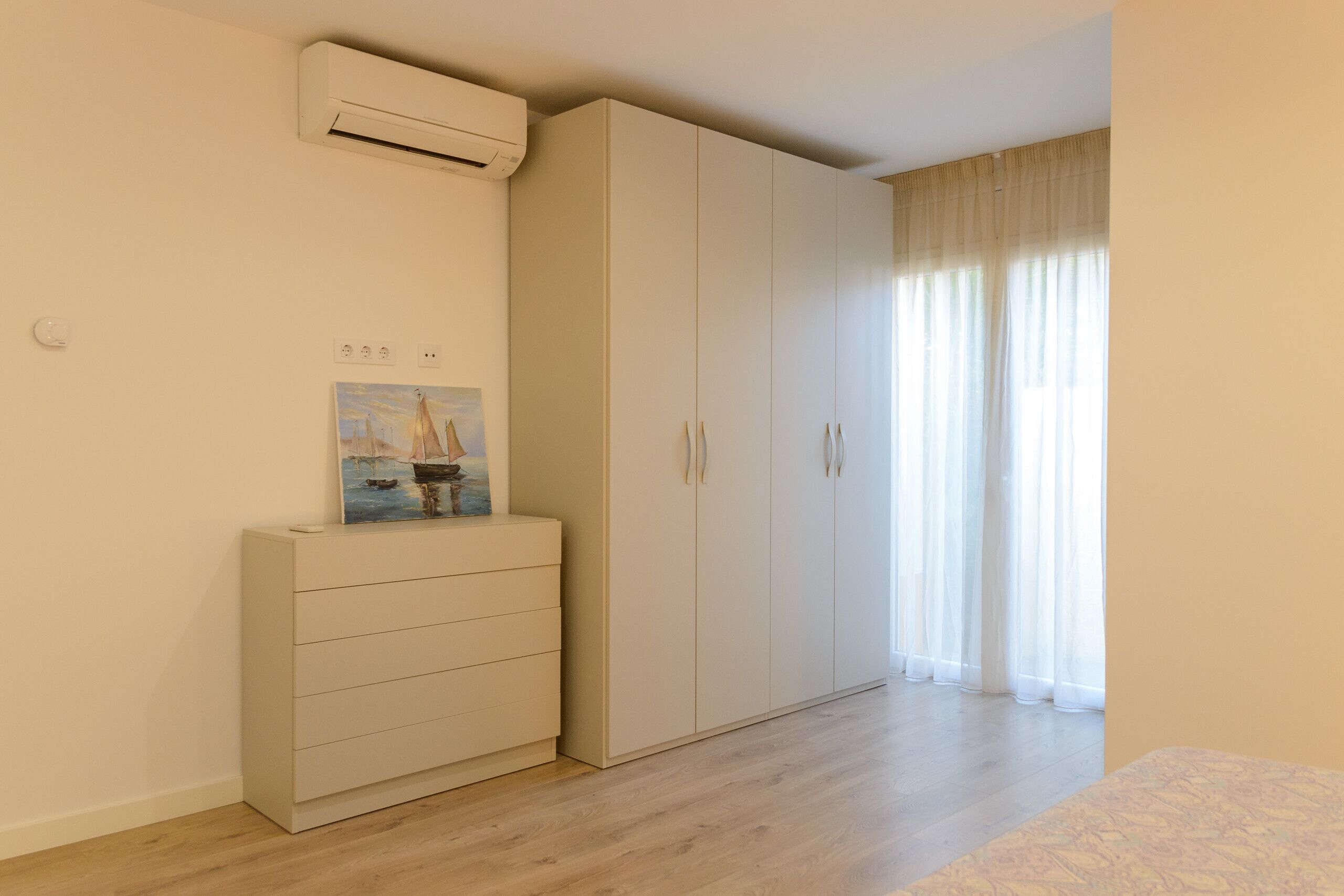 Une chambre à coucher avec un lit, une armoire, une commode et un tableau au mur.