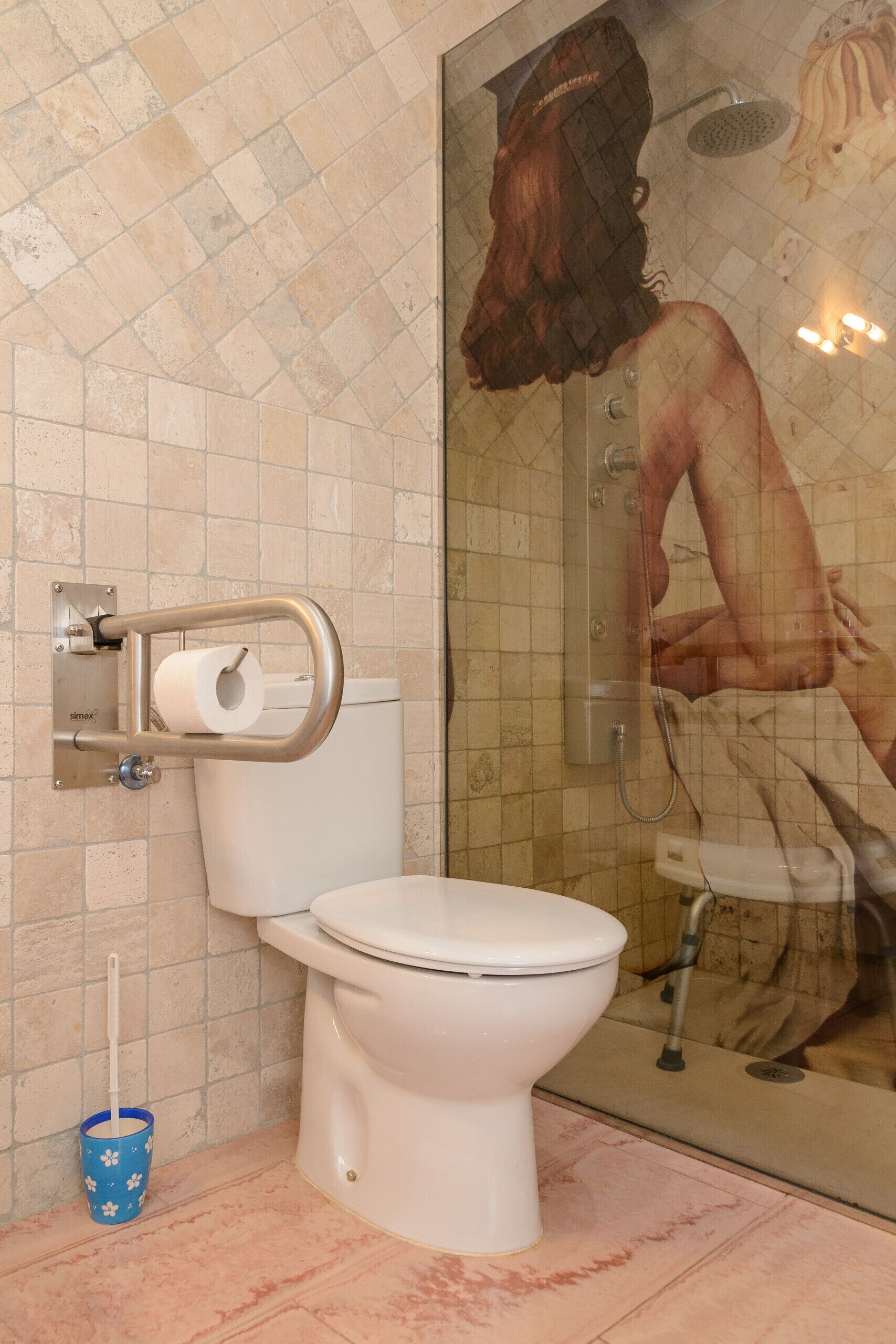 Een badkamer met toilet, douchewc en een glazen douchecabine.