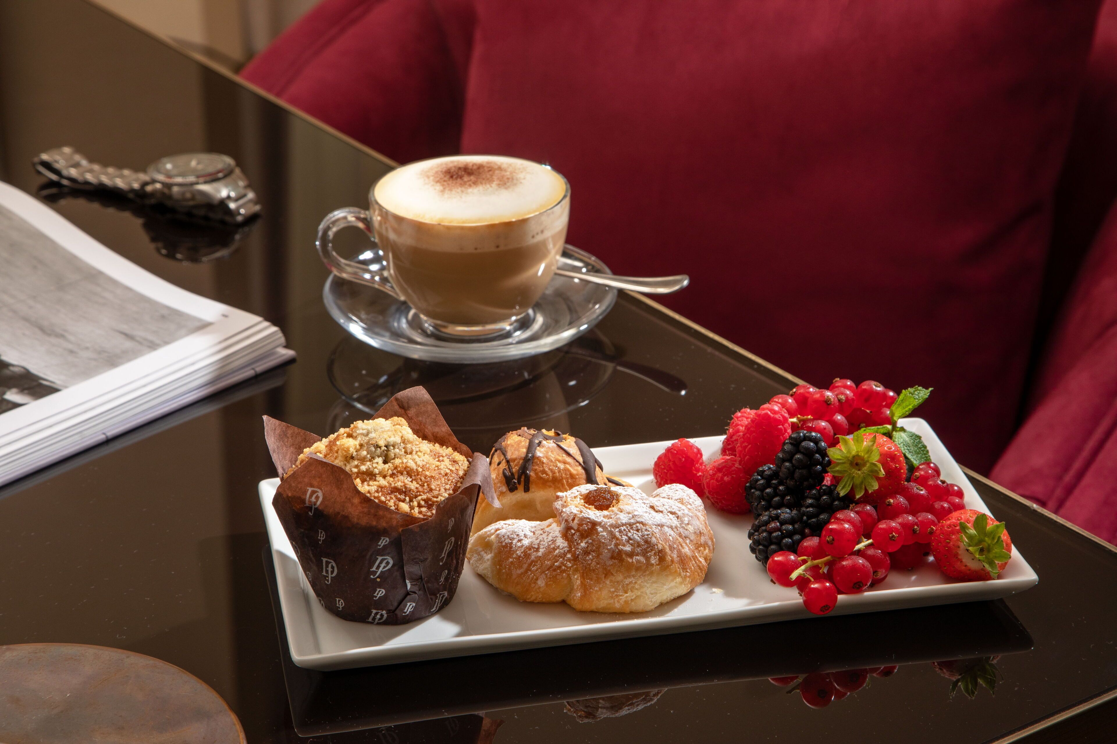 Une table avec une tasse de café, des pâtisseries et une assiette de fruits rouges.
