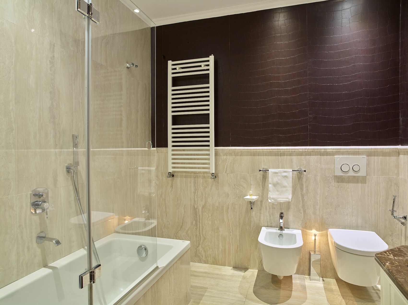 A modern bathroom with a glass-enclosed shower, a freestanding bathtub, a bidet, and a toilet.