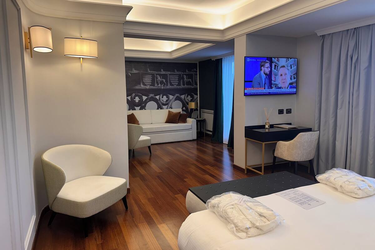 Une chambre d’hôtel moderne équipée d’un canapé, de deux fauteuils, d’un bureau et d’une télévision.