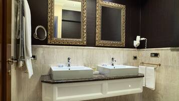 A bathroom with two sinks, a vanity, a towel rack, and two large mirrors with ornate frames.