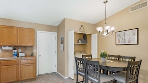 A kitchen with wooden cabinets, a dining table with chairs, a chandelier, and a wall-mounted picture. - Peaceful Valley - Rita Ranch/Tucson- 3BR/2BA/PrivatePool/NearShops&Restaurants (Tucson)