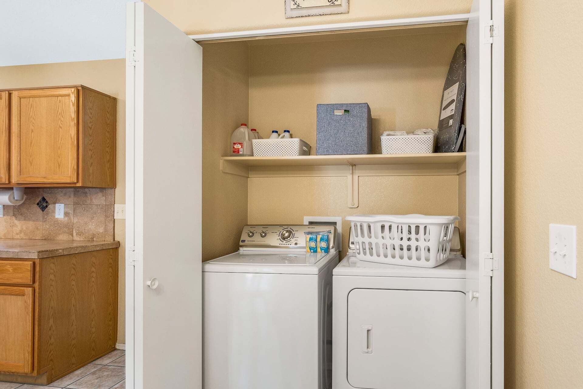 A laundry room with a washing machine, dryer, and shelves with laundry supplies.