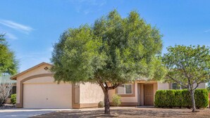 A residential house with a garage, a well-maintained lawn, and a small tree in the front yard. - Peaceful Valley - Rita Ranch/Tucson- 3BR/2BA/PrivatePool/NearShops&Restaurants (Tucson)