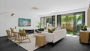 Relax in this stylish living room with a sofa, rocking chair, and flat-screen TV, surrounded by a view of the outdoors.