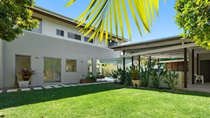Enjoy a serene outdoor space with a lush lawn and potted plants, complemented by a covered patio area.