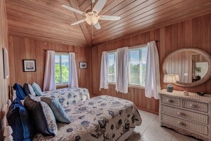 A wooden-paneled bedroom with two beds, a ceiling fan, and a dresser with a mirror. - Lookout House - Discover Tranquility (Hope Town)