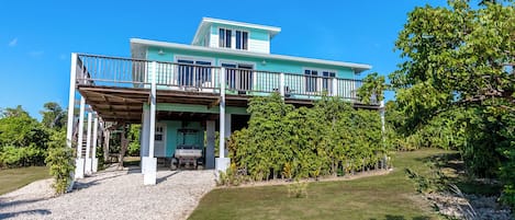 A two-story house with a covered porch, a car parked under the porch, and a well-maintained lawn.