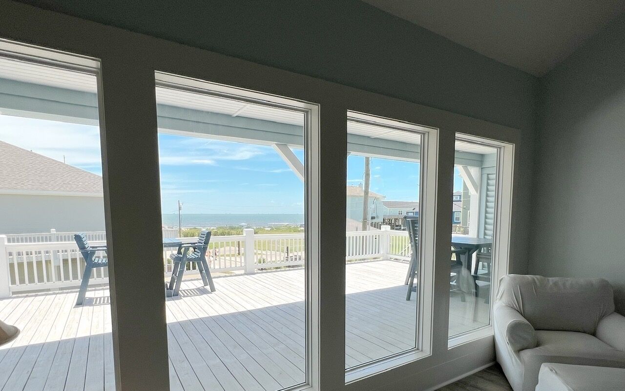 A room with large windows overlooking a deck with outdoor furniture.