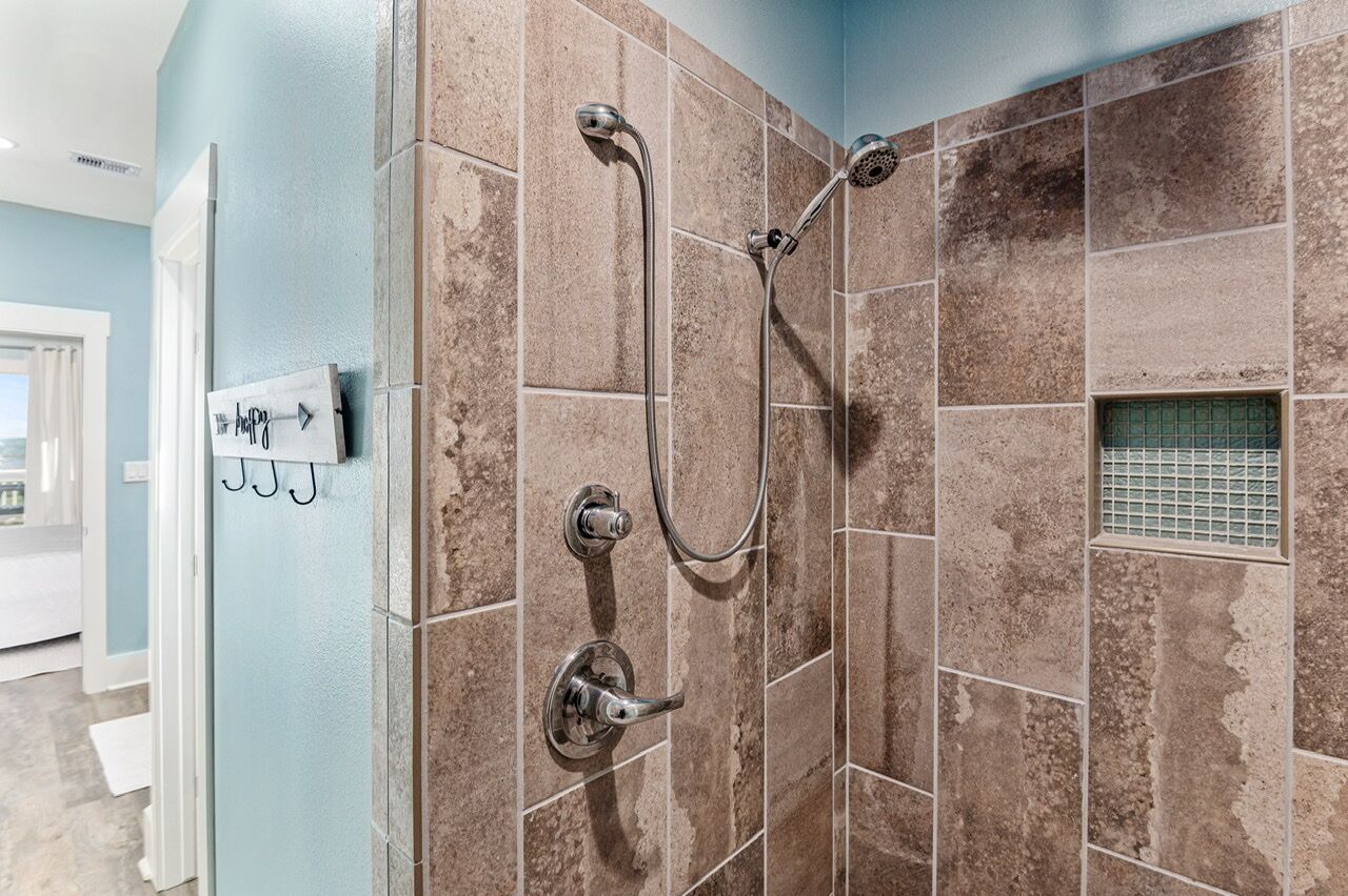 A shower with a handheld showerhead and a wall-mounted faucet.