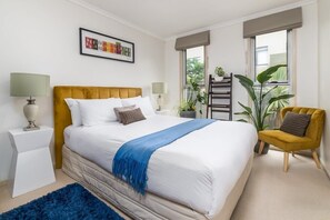 Relax in a serene space with a large bed, side tables, and a balcony offering a view of the outdoors.