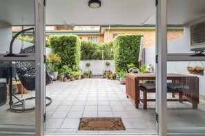 Relax in a serene outdoor space with a clean floor, potted plants, and a wooden table and bench.