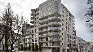 Un immeuble résidentiel à plusieurs étages, doté de balcons, d’un passage piéton et d’un panneau de signalisation.