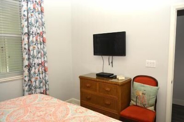A bedroom with a bed, a wooden dresser, a television mounted on the wall, and a chair with a cushion. - "Heron's Perch" Direct Ocean Front, Unit 743 at Cinnamon Beach (Palm Coast)