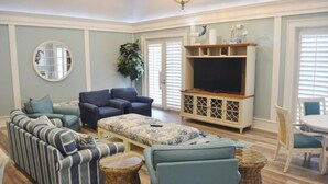 A spacious living room with a sectional sofa, two armchairs, a coffee table, a TV stand, and wicker side tables. - "Heron's Perch" Direct Ocean Front, Unit 743 at Cinnamon Beach (Palm Coast)
