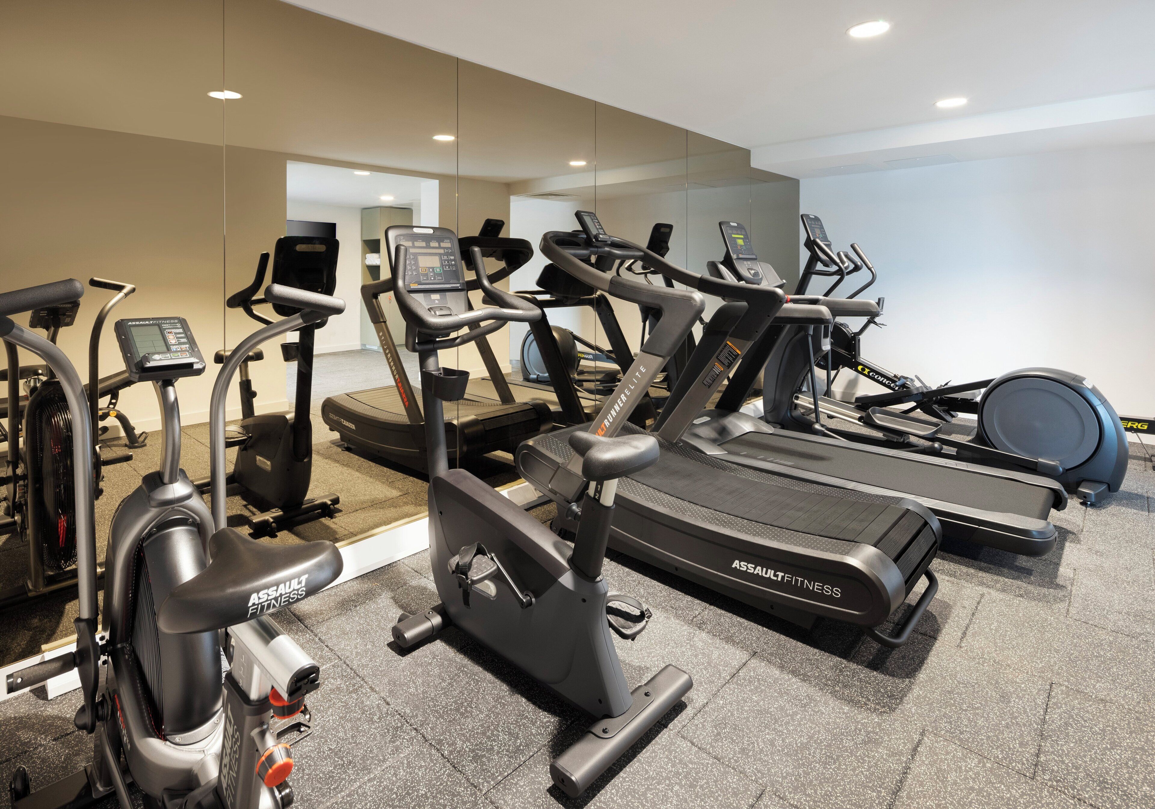 Un gimnasio con varias máquinas de cardio, incluyendo cintas de correr y bicicletas estáticas.
