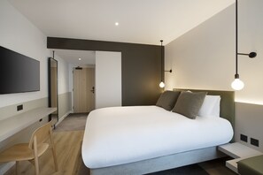 A modern hotel room with a large bed, a desk, a chair, and a TV mounted on the wall. - Leonardo Hotel Manchester Piccadilly (Manchester)