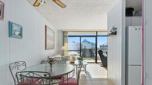 Una cocina compacta con comedor, refrigerador y vista a un edificio a través de un ventanal.