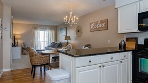 A modern kitchen with white cabinetry, a black stove, and a chandelier.