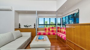 A modern living room with a white sofa, a wooden cabinet, and a colorful sofa set. - Pet-friendly 4BR coastal home with water views, timber deck and linen included (Evans Head)