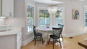 Enjoy meals in this kitchen with a central island, dining table, and large windows offering views of the outdoors.