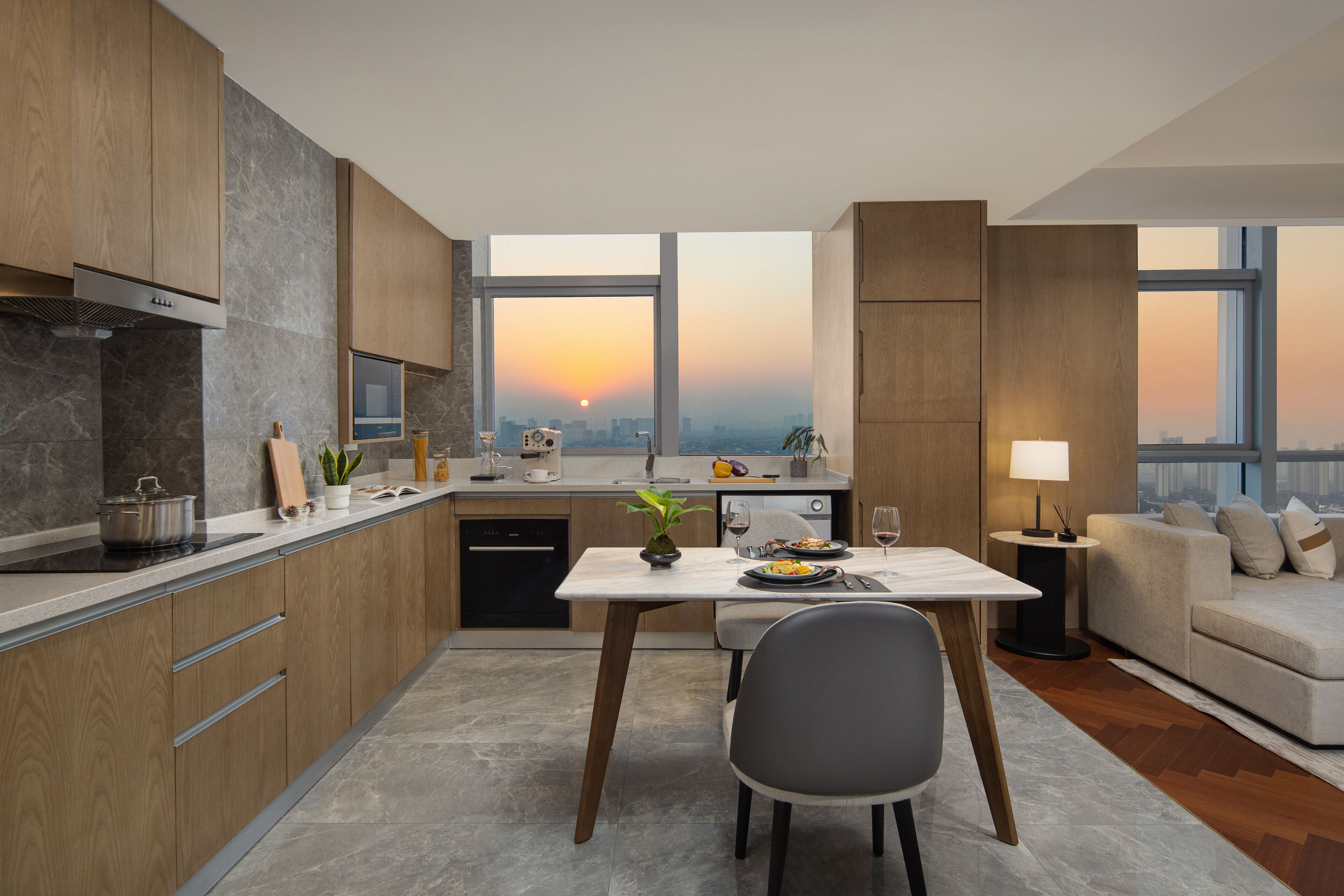 Una cocina moderna con comedor, amplios ventanales y vistas al atardecer y al paisaje urbano.
