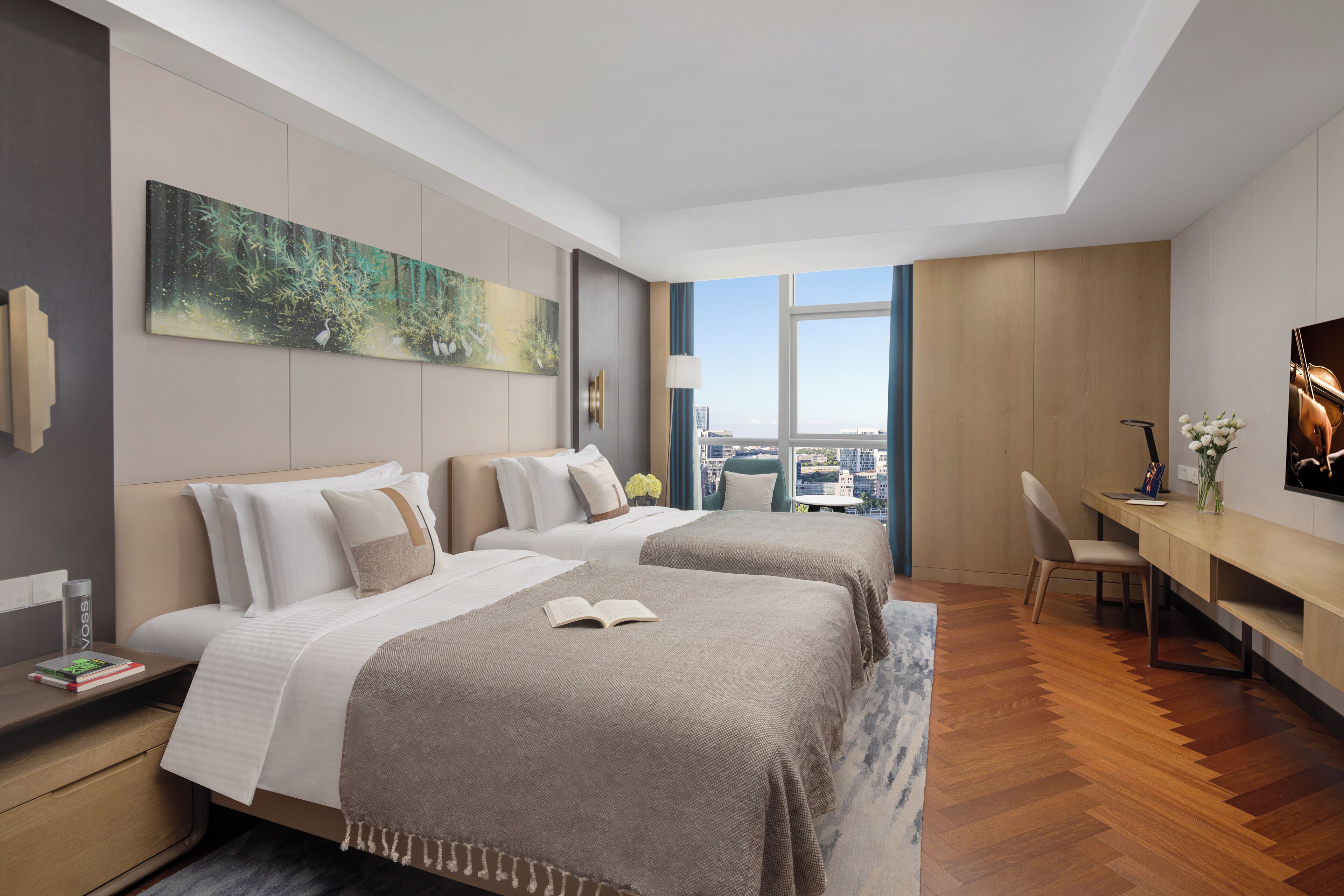A modern hotel room with two beds, a desk, and a large window offering a city view.