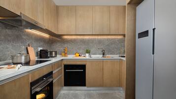 Una cocina moderna con armarios de madera, horno empotrado, lavavajillas y refrigerador de acero inoxidable.
