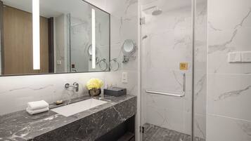 Un baño moderno con lavamanos de mármol, un espejo grande y una cabina de ducha con paredes de vidrio.