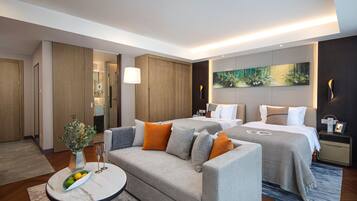 A modern hotel room with a sofa, two beds, a small table, and a painting on the wall.