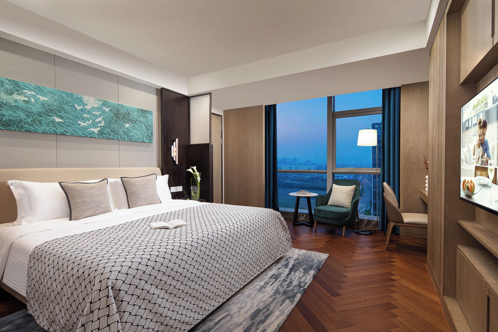 A modern hotel room with a large bed, a seating area with a view, and a television.