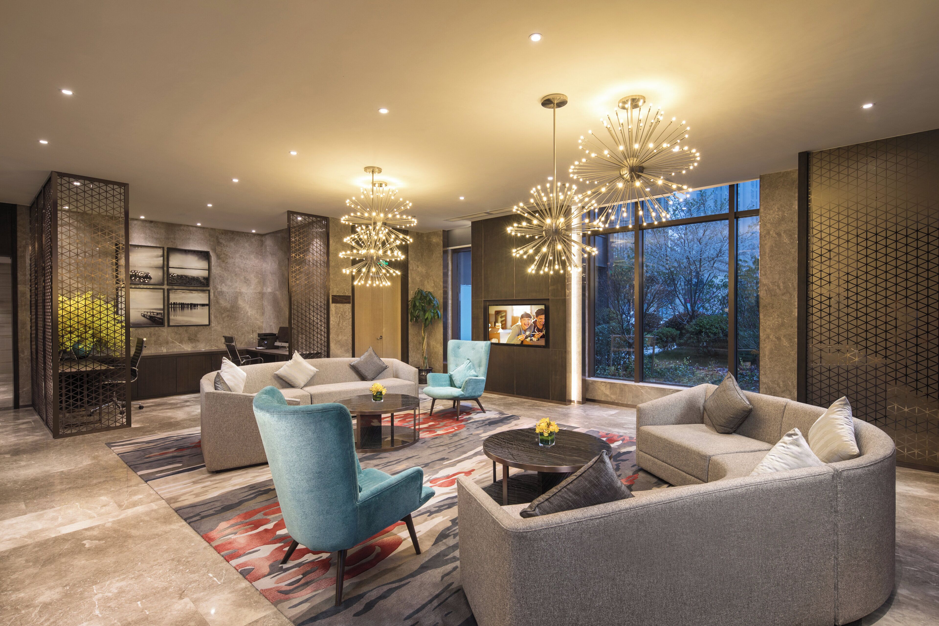 Een moderne woonkamer met een bank, fauteuils, een salontafel en een televisie.