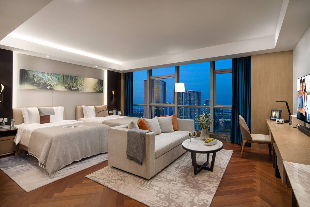 Une chambre d’hôtel moderne dotée d’un grand lit, d’un canapé, d’un coin repas et offrant une vue sur la ville.