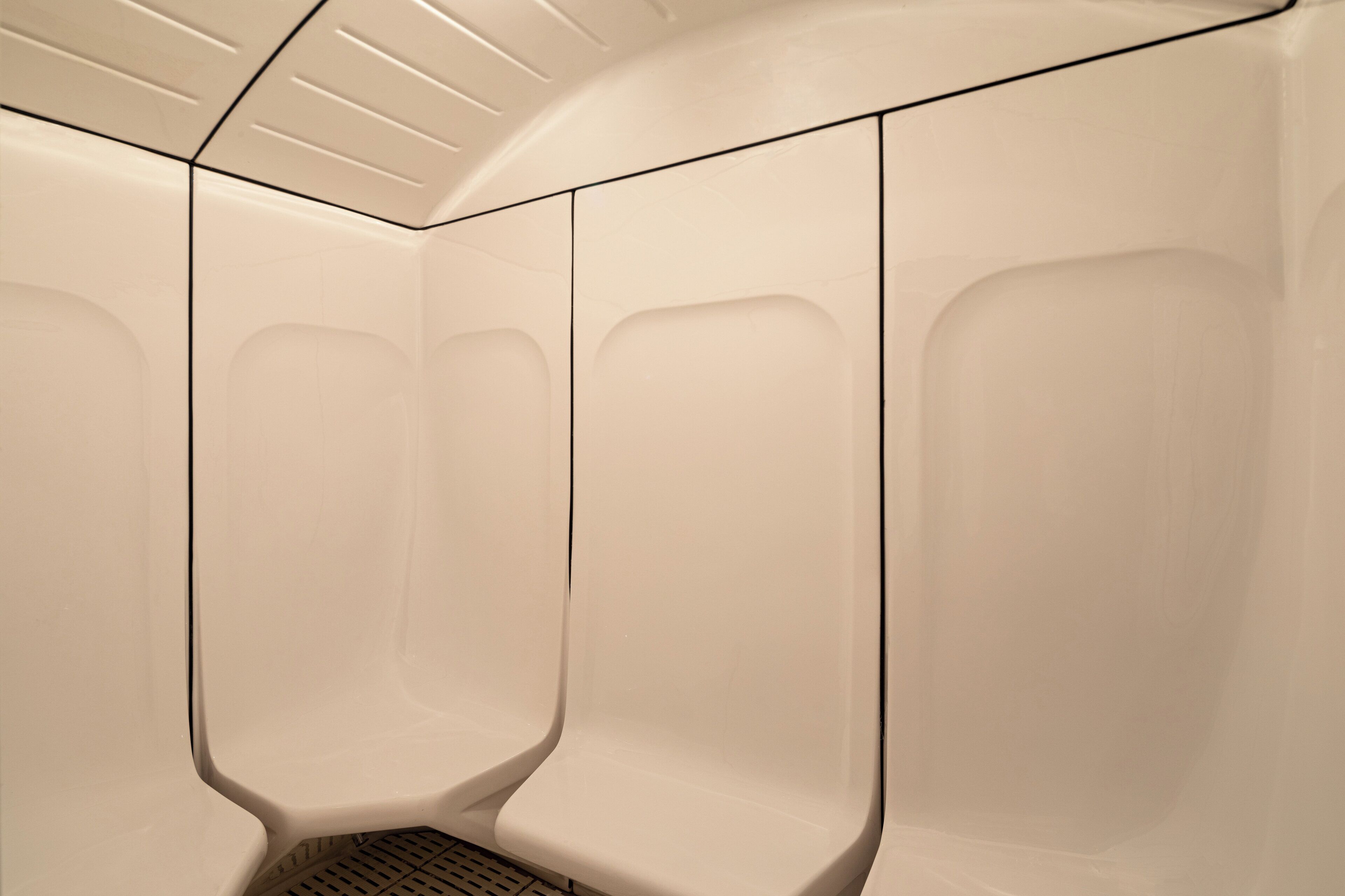 Ein modernes Badezimmer mit minimalistischem Design, das durch eine gewölbte Decke und einen zentralen Ablauf gekennzeichnet ist.