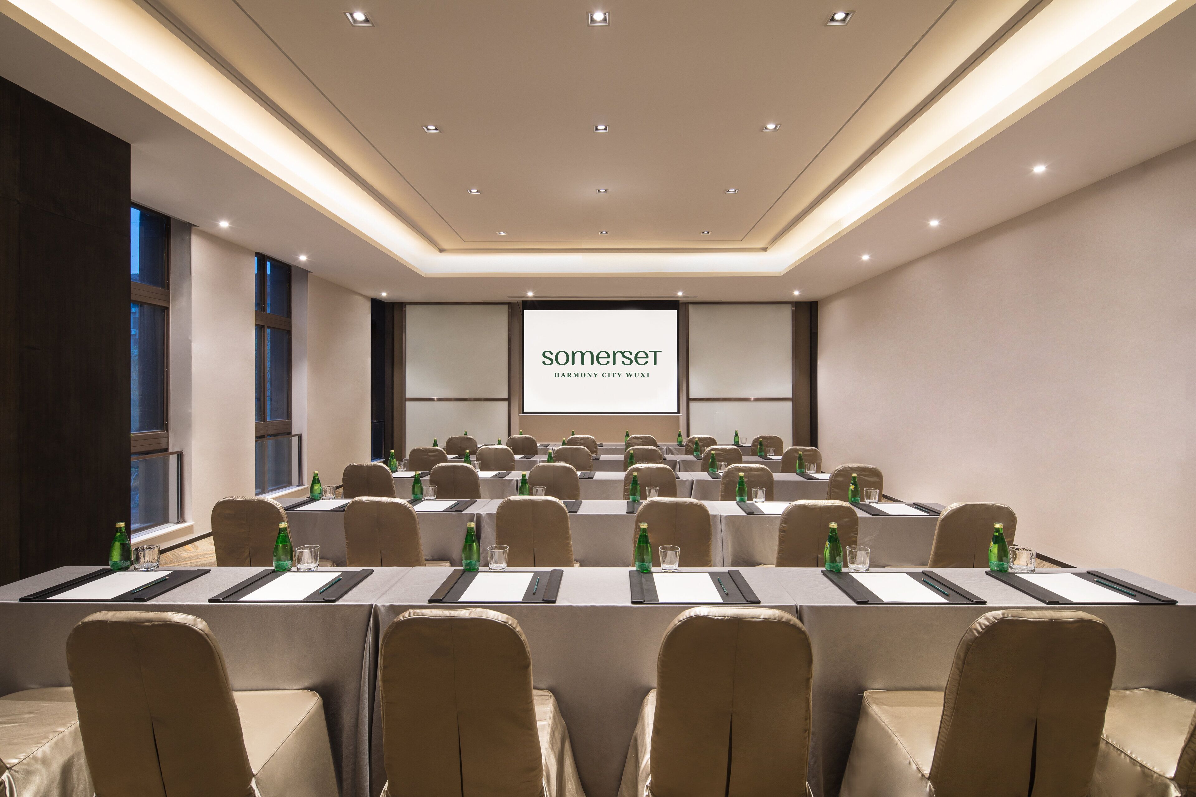 A conference room with multiple tables, chairs, and a projector screen displaying "somerset".